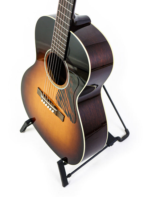 Acoustic guitar on stand against white background.