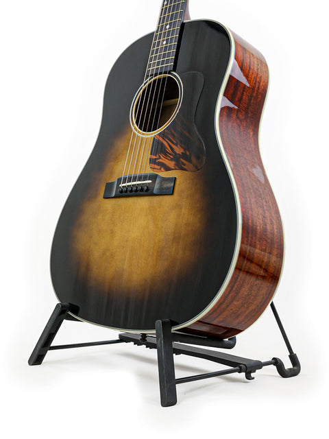 Acoustic guitar with a sunburst finish on a stand, against a white background.