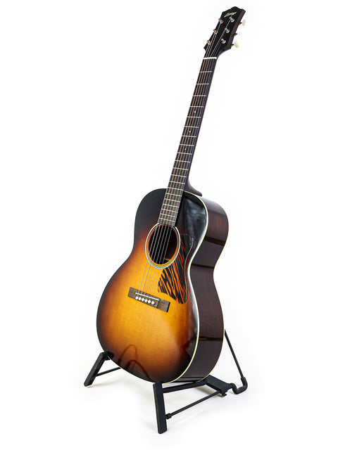 Acoustic guitar with sunburst finish on a stand against a white background.