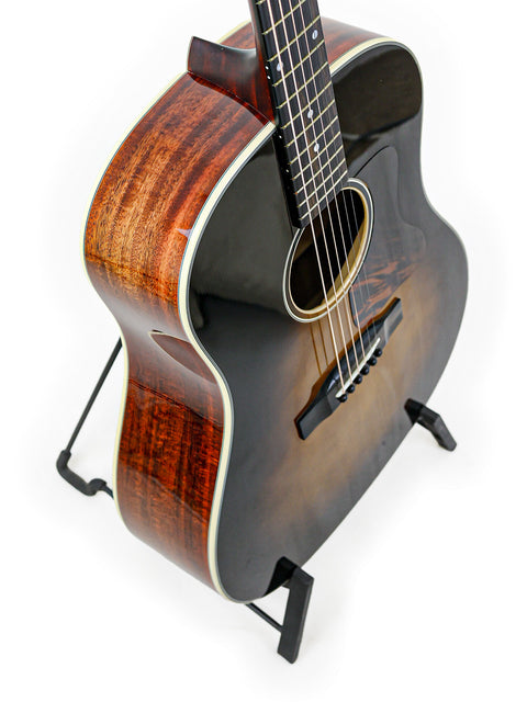 An acoustic guitar on a stand against a white background.