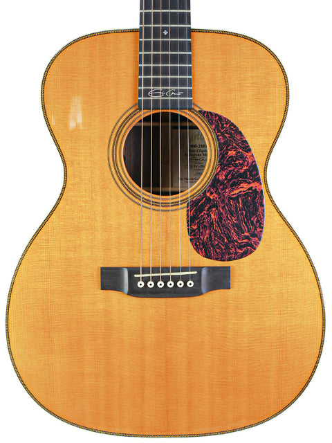 An acoustic guitar with a wooden body and black pickguard, featuring the Martin 000-28EC Eric Clapton Signature model from 2006.