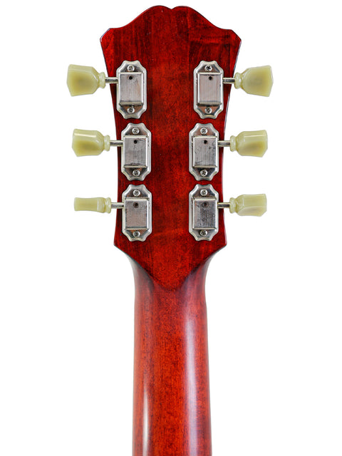Back of a guitar headstock with six tuning pegs, on a red wooden background.