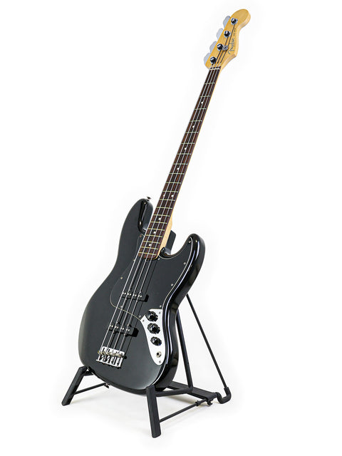 Black Fender Jazz Bass guitar on a stand against a clean white background, showcasing its sleek design and craftsmanship.
