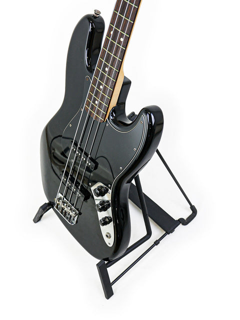 Black Fender Jazz Bass guitar on a stand, featuring a minimalist white background that highlights its elegant shape.