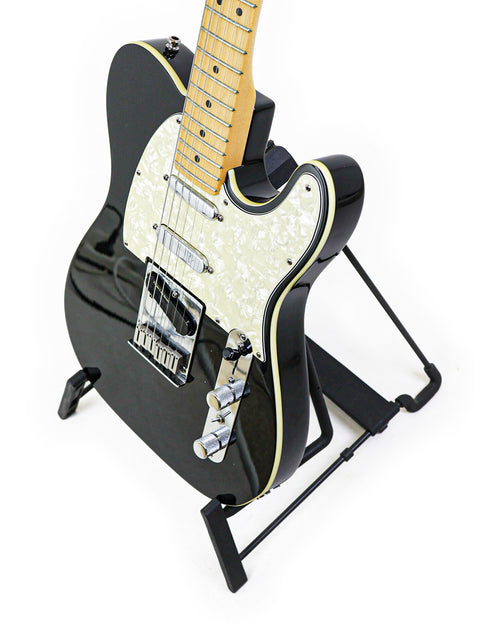 Black Fender Tele Plus V2 guitar from 1999 positioned on a stand with a stark white backdrop.