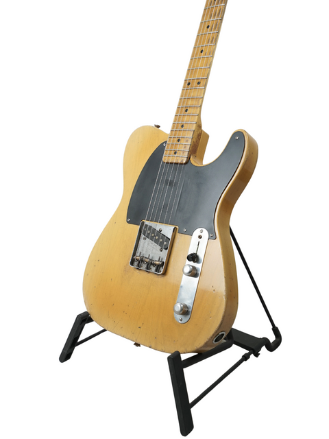 Bright yellow Nacho Guitars 50s Stratocaster resting on a black stand, perfect for any music lover's collection.