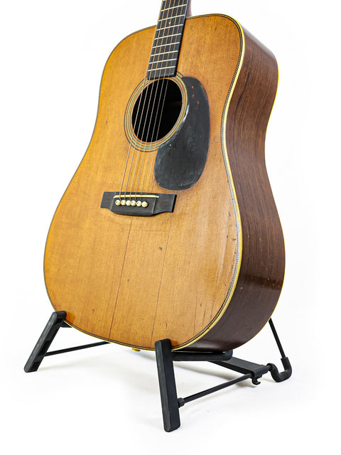 Classic 1943 Martin D-28 guitar resting on a stand, highlighted by a bright white background.