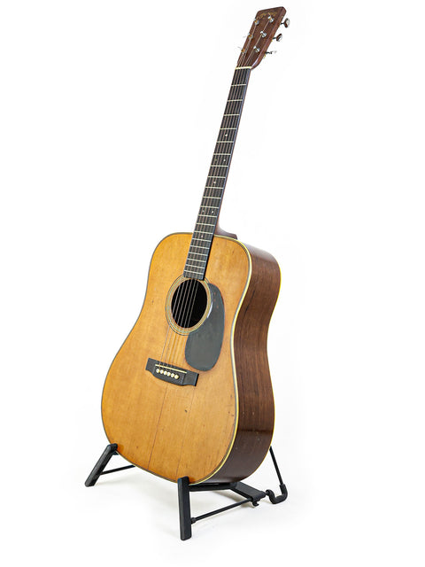 Classic 1943 Martin D-28 guitar resting on a stand, highlighted by a simple white background.