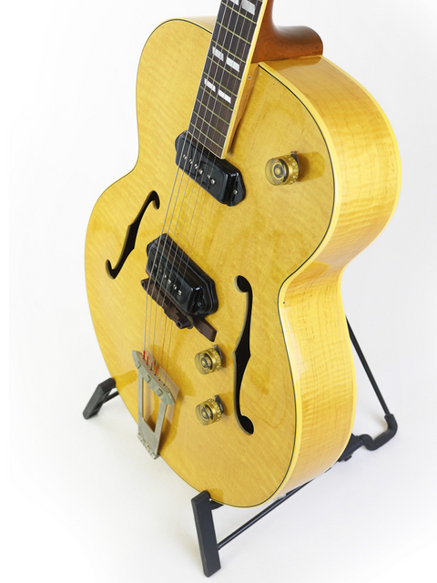 Classic 1952 yellow Gibson ES-300 guitar elegantly positioned on a stand with a bright white background.