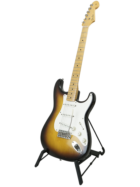 Classic 1957 Fender Stratocaster on a stand, beautifully displayed against a white backdrop, capturing its timeless elegance.

