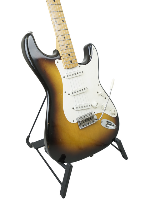 Classic 1957 Fender Stratocaster on a stand, elegantly displayed against a bright white background.