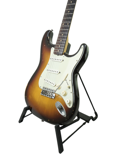 Classic 1959 Fender Stratocaster guitar on a stand, highlighted by a simple white background for a timeless look.