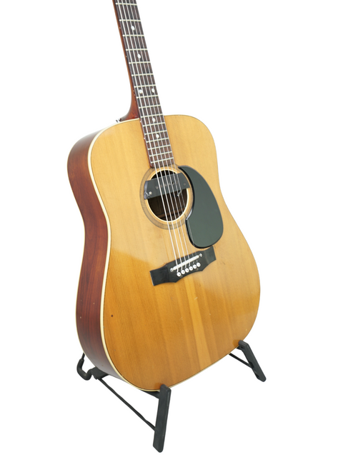 Classic 1972 Maton FG100 guitar resting on a stand, highlighted by a simple white background.