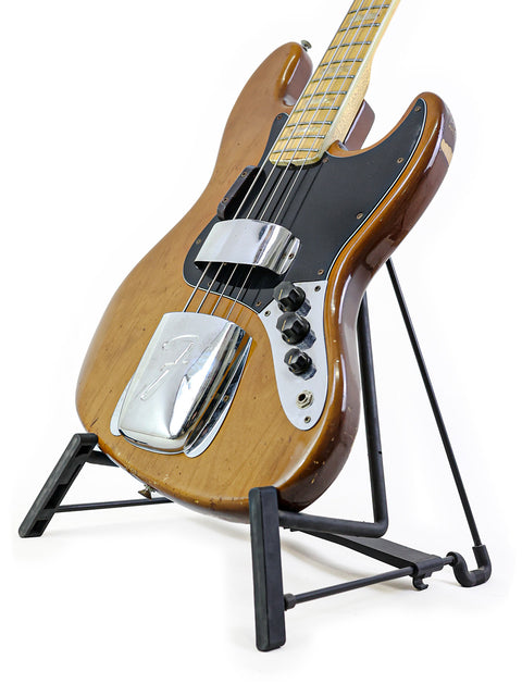 Classic 1974 Fender Jazz Bass resting on a stand with a black base, highlighting its vintage charm and iconic look.