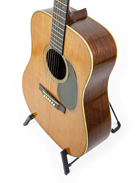 Classic Martin D-28 guitar from 1943 resting on a stand, highlighted by a bright white background.