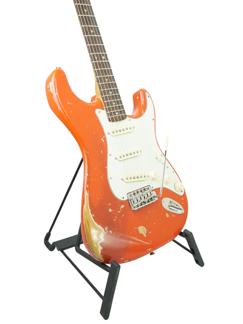 Classic orange Fender Stratocaster from 1979 resting on a stand, highlighted by a white background.