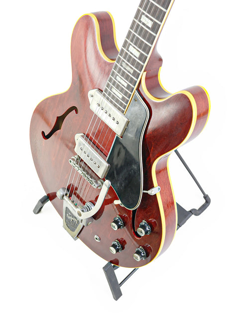 Classic red Gibson ES-330 from 1965, showcased on a stylish black stand.