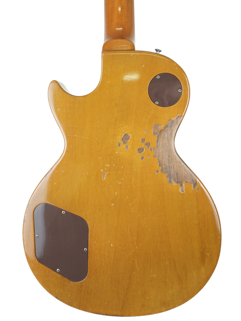 Close-up of a Gibson Les Paul 1956 Reissue guitar featuring a wooden body and a rich brown headstock, beautifully relic'd.