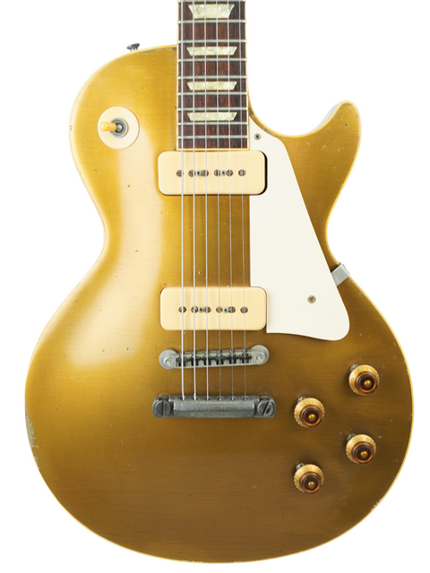 Close-up of a gold Les Paul guitar with a white pickguard, highlighting its 1956 reissue craftsmanship from Gibson Custom Shop.