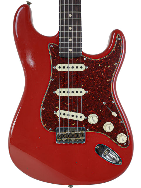 Close-up of a red Fender Custom Shop 1961 Stratocaster Hardtail guitar featuring a sleek black pickguard, highlighting its craftsmanship.

