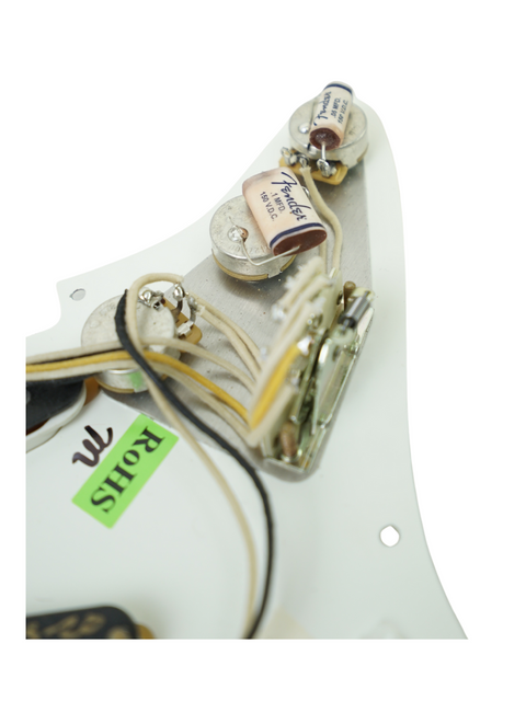 Close-up of a white Fender Custom Shop 1955 Relic Stratocaster, featuring a pickup and wires, highlighting its classic appeal.
