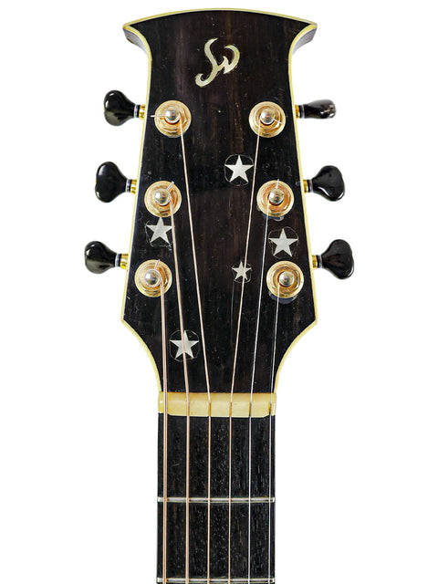 Close-up of an acoustic guitar headstock, showcasing intricate tuning pegs and wood grain, labeled Jim Williams WD-40, Australia 2005.