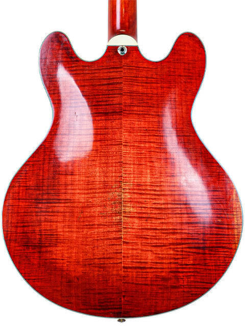 Close-up of the back of a red wooden electric guitar body with a vibrant grain pattern.