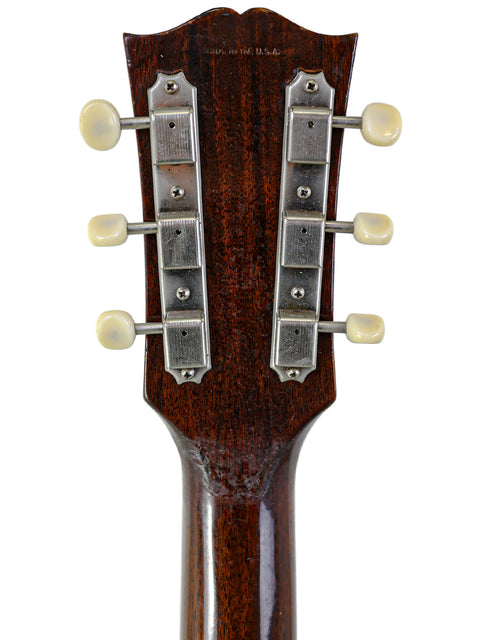 Close-up of the headstock on a 1954 Gibson LG-1 guitar, highlighting its wooden body and vintage craftsmanship.
