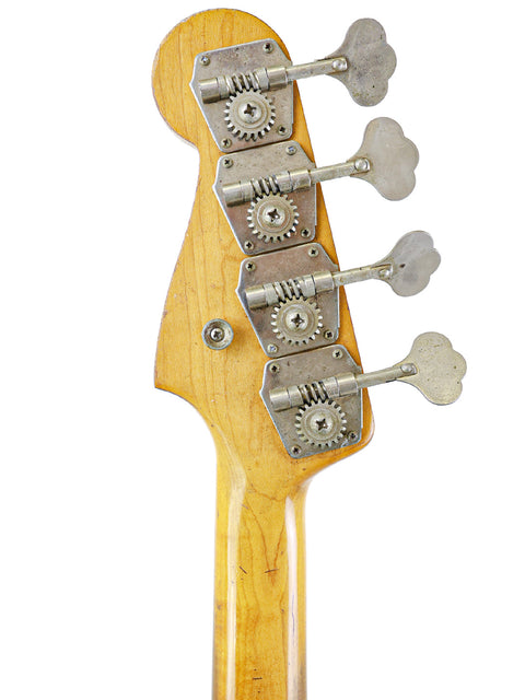 Close-up shot of a vintage 1963 Fender Precision Bass guitar head showcasing four tuning knobs.
