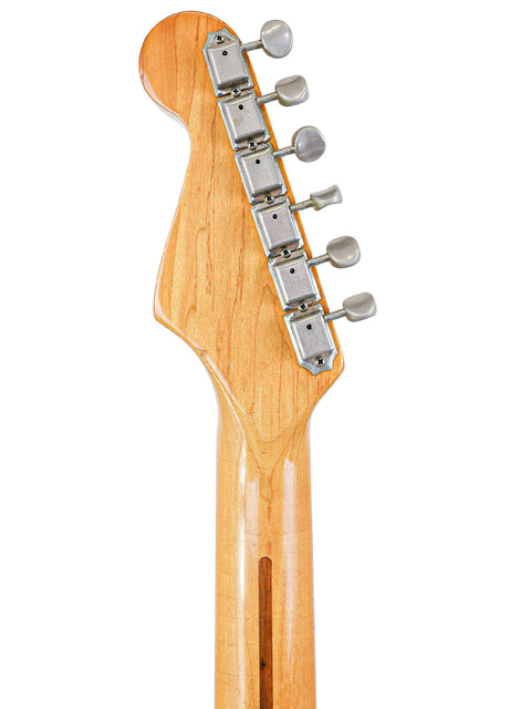 Close-up shot of a vintage Fender AVRI ‘57 Stratocaster guitar head, featuring a rich wooden body and classic vintage style.