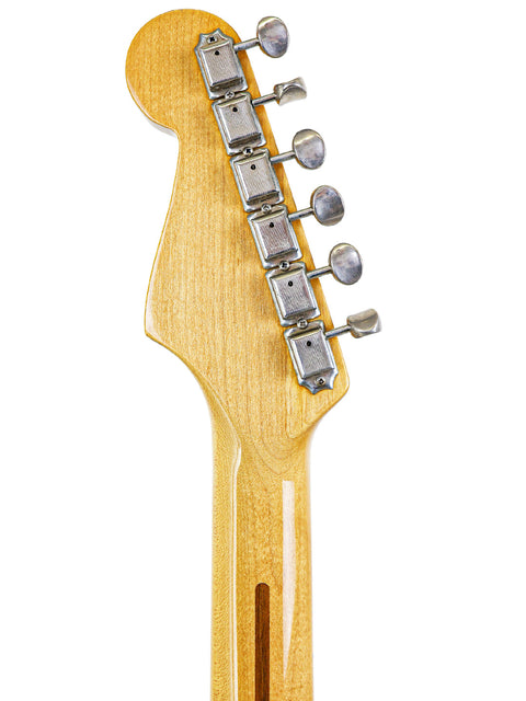 Close-up view of a vintage Fender AVRI ‘57 Stratocaster headstock, featuring its iconic wooden body from 1985.