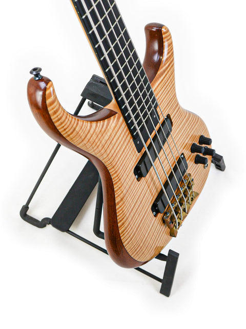 Detailed shot of the lower body of the Alembic Orion bass guitar, highlighting the natural wood grain and high-quality bridge.