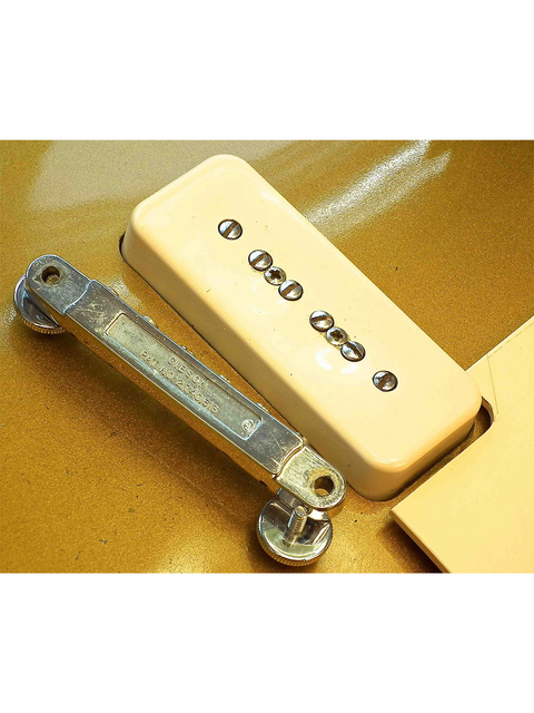  Detailed view of a white guitar pickup alongside a metal plate, featuring a vintage 1968 Gibson Les Paul Standard Goldtop.
