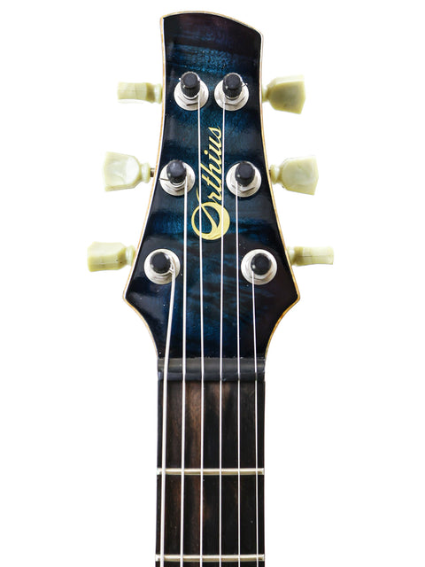 Detailed view of the headstock of an electric guitar, the Orthius Deluxe DC, with a bold blue background enhancing its aesthetic.