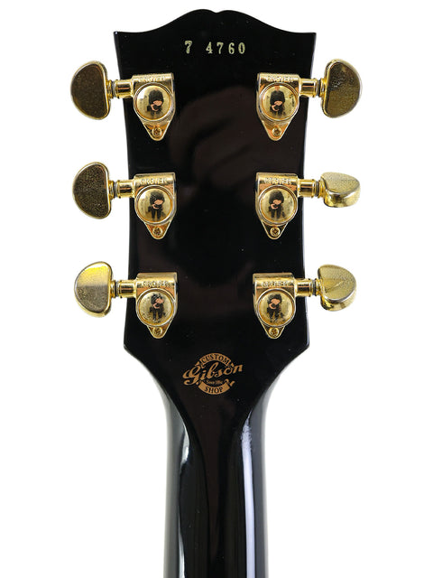 Detailed view of the headstock on a 2004 Gibson Custom Shop 1957 Les Paul Custom B3 'Black Beauty' electric guitar.
