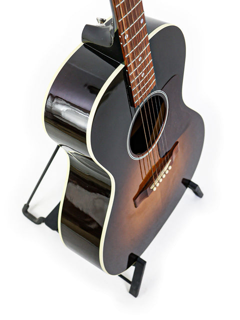 Elegant Gibson L-00 Standard Vintage Sunburst guitar resting on a stand, highlighted by a pristine white background.
