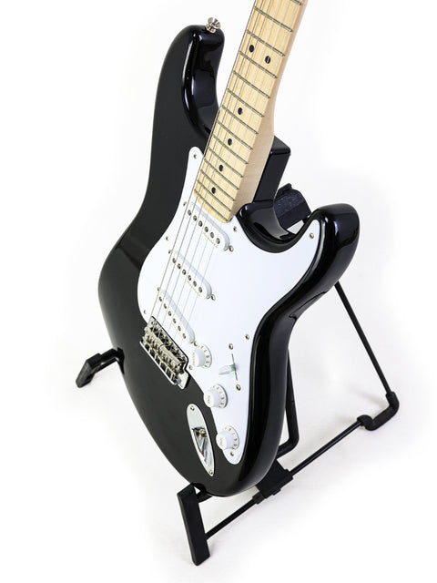Fender Eric Clapton "Blackie" Stratocaster in black, displayed on a stand with a white backdrop.