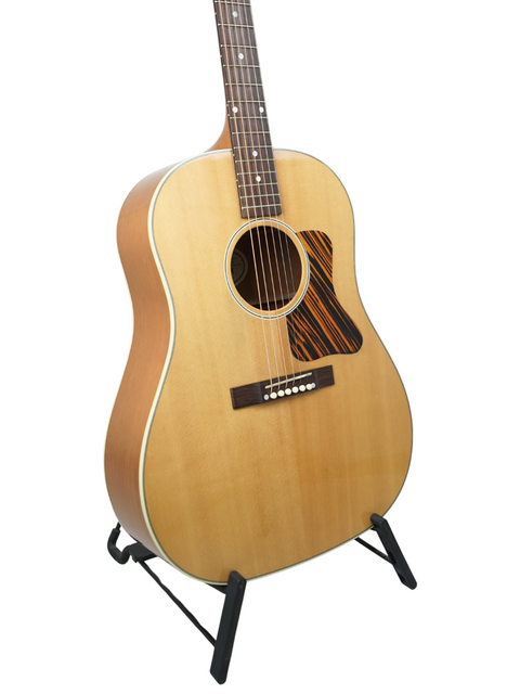 Gibson J-35 guitar on a stand, elegantly displayed against a clean white background, showcasing its classic design.
