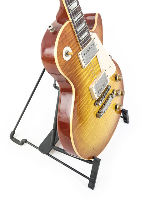Gibson Les Paul '59 Reissue guitar resting on a stand, with a minimalist white background emphasizing its classic style.