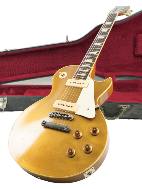 Gold 1956 Gibson Les Paul guitar with a case, showcased on a white surface.