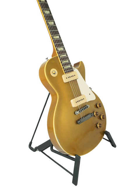 Gold electric guitar on a stand, featuring a Gibson Custom Shop Les Paul 1956 Reissue design.