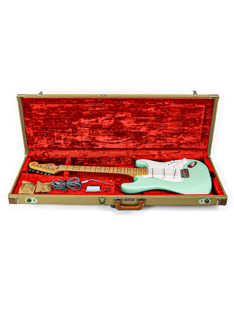 Green Fender AVRI ‘57 Stratocaster guitar nestled in a case, surrounded by luxurious red velvet.