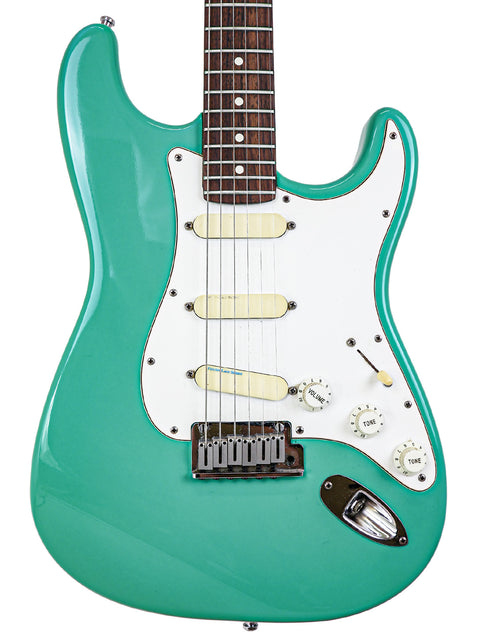 Green electric guitar, Fender Strat Plus Deluxe model from 1989, featuring a white pickguard.
