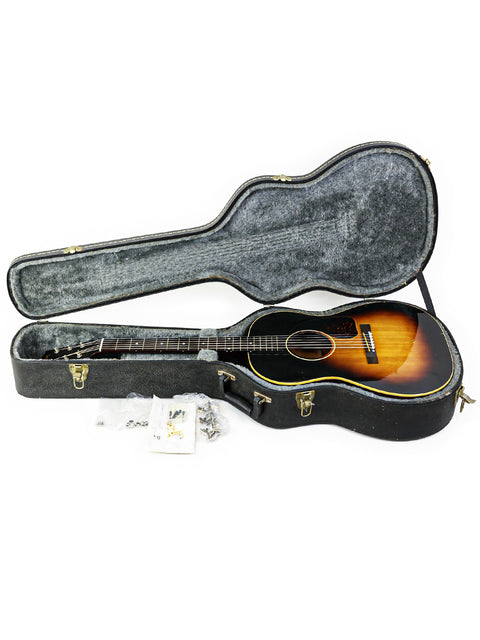 Inside a guitar case, a 1954 vintage Gibson LG-1 rests, representing classic American guitar artistry.