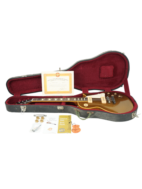 Inside a guitar case, a Gibson Custom Shop Les Paul 1956 Reissue and a certificate are displayed together.
