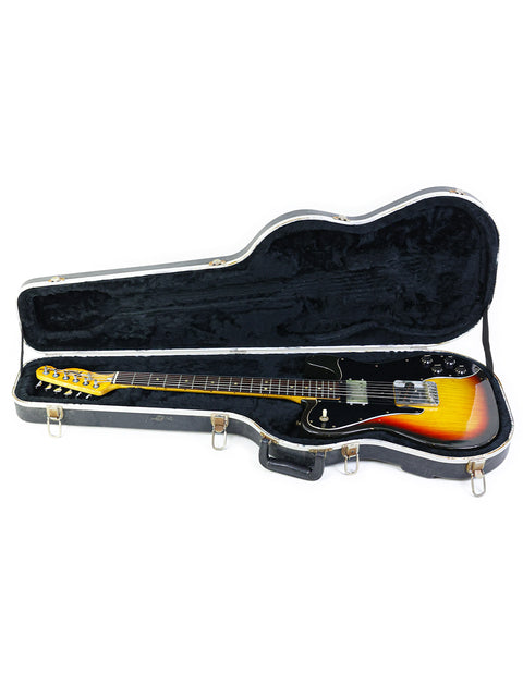 Inside a guitar case, a yellow and black Fender Telecaster Custom from 1977 is displayed, highlighting its classic design.
