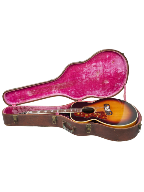 Inside a vintage Gibson J-200 left-handed guitar case from 1955, a striking pink interior adds a pop of color.