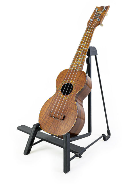 Kumalae ukulele from the 1920s is displayed on a stand, representing the rich musical heritage of Hawaii.