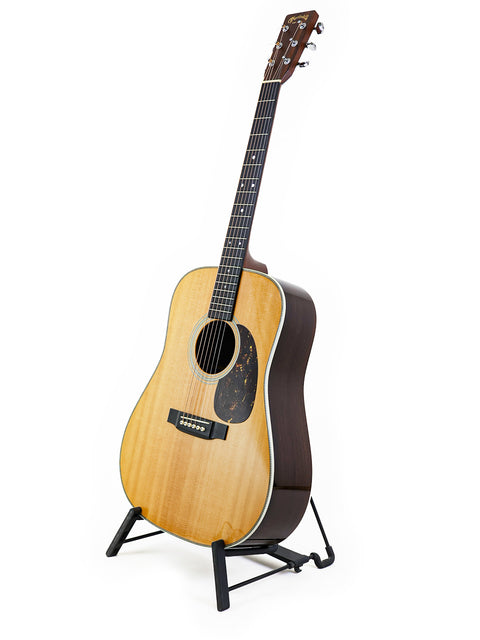 Martin HD-28 guitar from 2006 resting on a stand with a white backdrop.