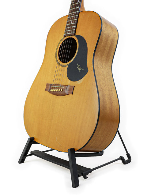 Maton M225 guitar from 1996, Australia, elegantly positioned on a stand with a simple white backdrop.